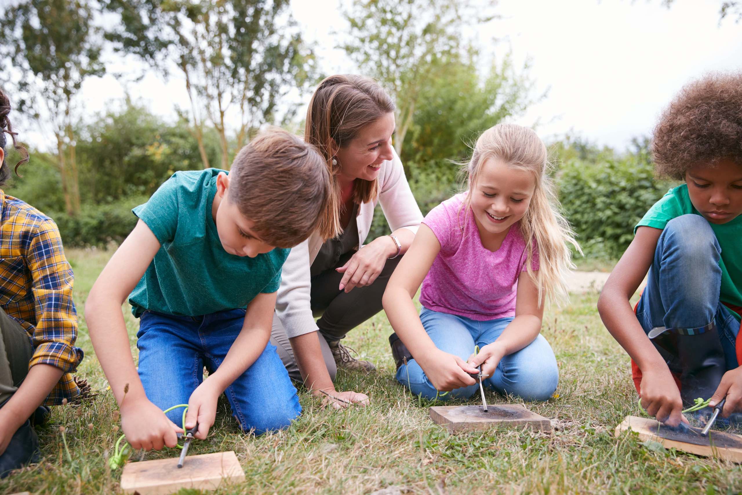 Mujer entrenando a niños de campamentos en estados unidos a hacer fuego. Niños alegres de aprender y vivir nuevas experiencias.